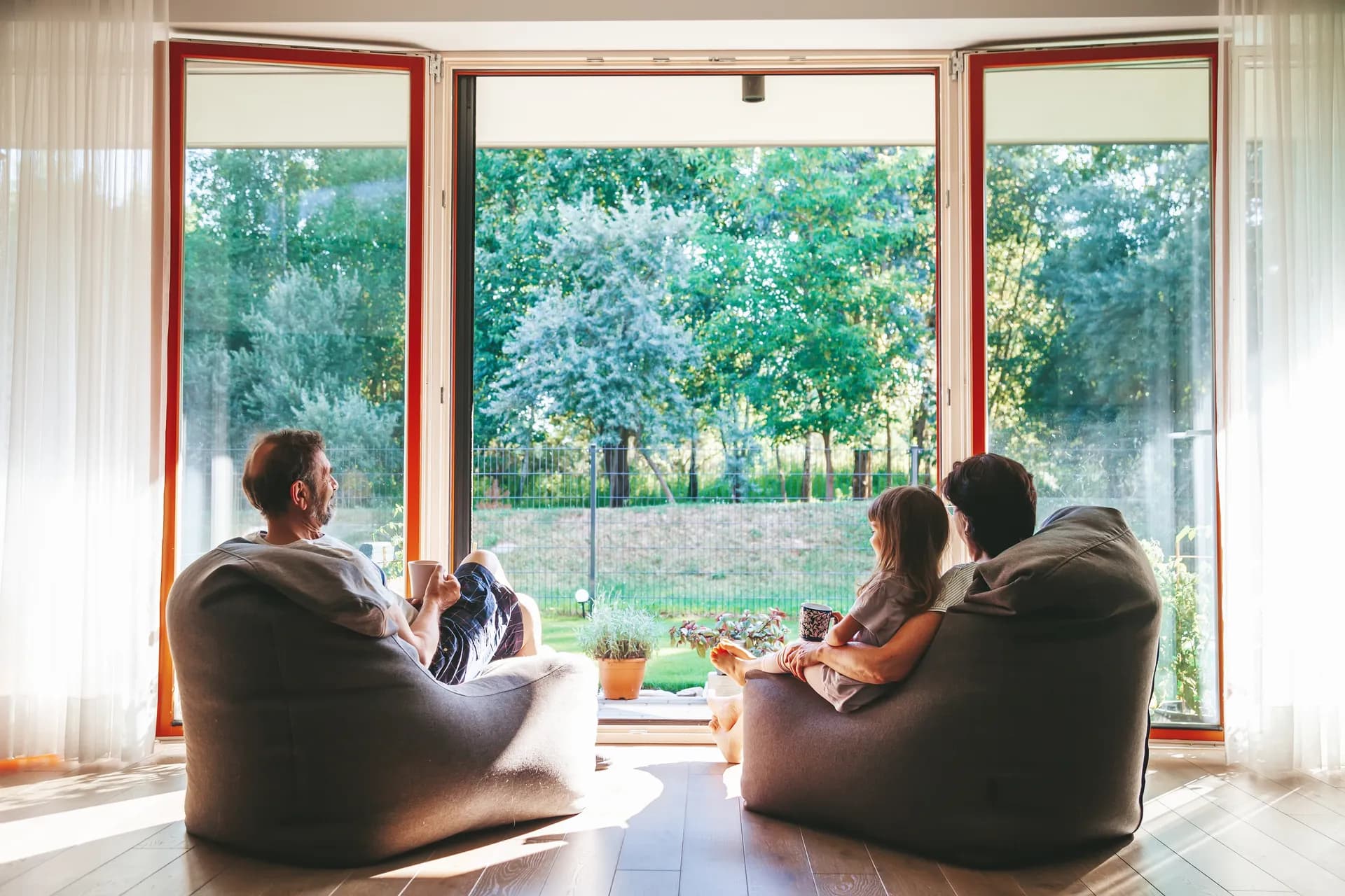 People relaxing by large windows overlooking trees